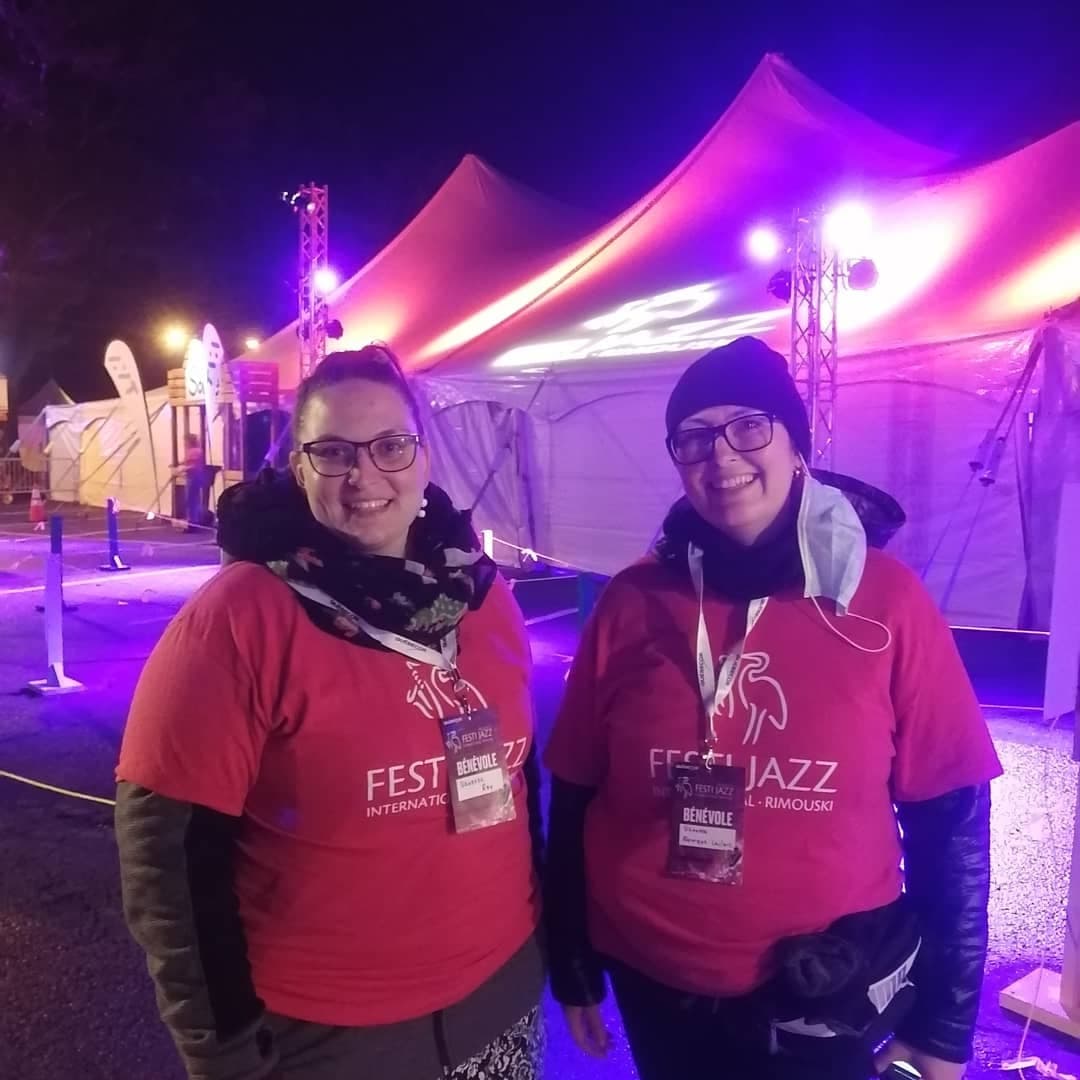 Deux bénévoles souriantes à l'accueil devant chapiteau de la Place Festi Jazz Québecor